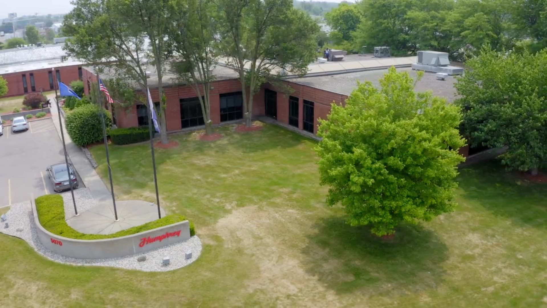 Aerial view of Humphrey Products headquarters in Kalamazoo, Michigan, featuring brick building, Humphrey sign, and flagpoles